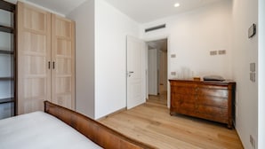 Ein Schlafzimmer mit einem hölzernen Bett, einem Kleiderschrank, einer Kommode und einer Tür zu einem anderen Raum.