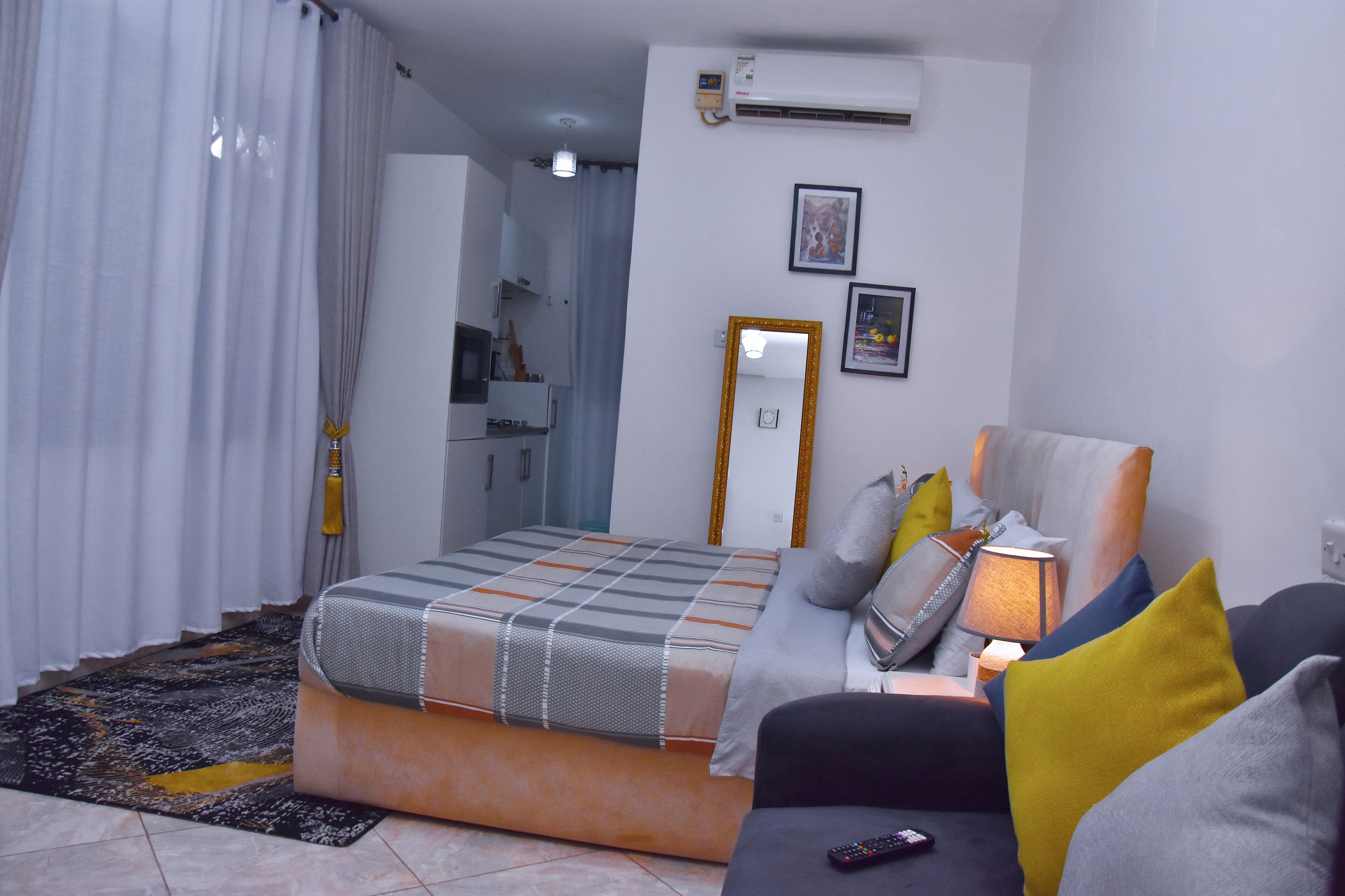 A bedroom with a bed, a sofa, a lamp, and a mirror.