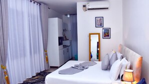 A hotel room with a bed, bedside lamp, and a mirror. - Cozy Studio Near UN Base | 5-Min Drive to Entebbe Airport (Entebbe)
