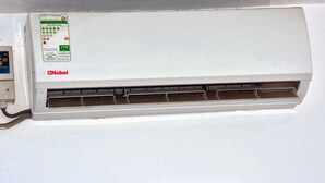 A white air conditioner unit with a sticker indicating energy efficiency and brand. - Cozy Studio Near UN Base | 5-Min Drive to Entebbe Airport (Entebbe)