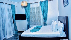 Ein Schlafzimmer mit Bett, Vorhängen, Fernseher und Fernbedienung.