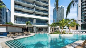A modern hotel with a swimming pool, outdoor seating, and high-rise buildings in the background. - Chic 2-bedroom apartment in vibrant Miami (Miami)