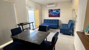 A modern living room with a dining table, blue sofas, and a painting on the wall. - Residencia Altavela Privada 51 (Valle de Banderas)