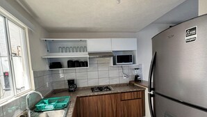 A modern kitchen with white cabinets, a stainless steel refrigerator, and a window providing natural light. - Residencia Altavela Privada 51 (Valle de Banderas)