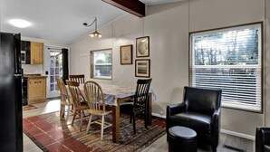 A dining area with a table, chairs, and a black leather chair. There is a window with blinds and a door leading to the kitchen. - Charming 2-bedroom in Florence within blocks of the beach, pet friendly, hot tub (Florence)