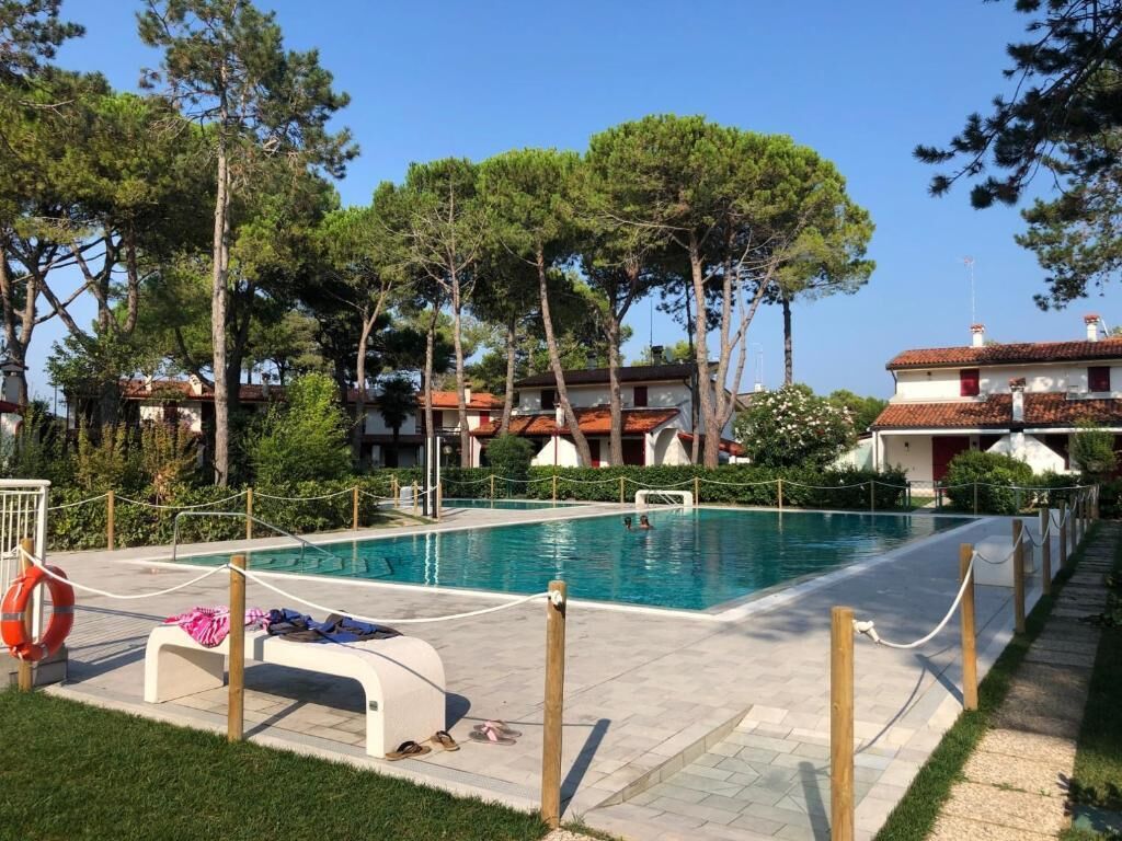 A swimming pool with lounge chairs, surrounded by trees and buildings.