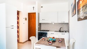 Een kleine keuken met witte kastjes, een houten deur en een eettafel gedekt met kopjes en een decoratief middelpunt.