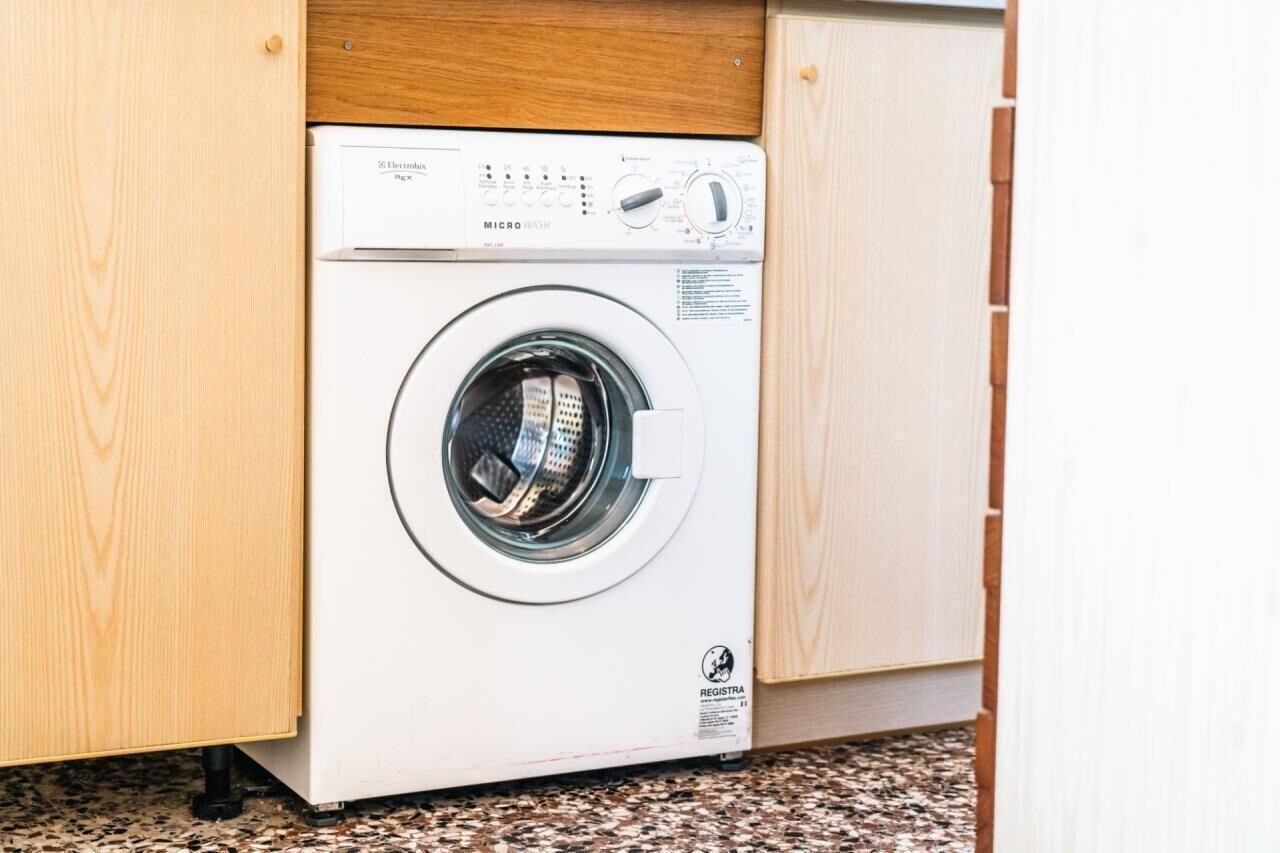 Un lave-linge à chargement frontal dans une cuisine avec des meubles en bois.
