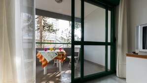 Ein Zimmer mit einer Schiebetür zu einem Balkon im Freien, ausgestattet mit Tisch und Stühlen.