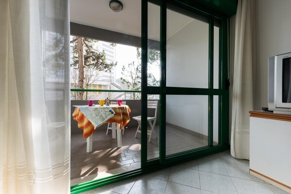 A room with a sliding glass door leading to an outdoor balcony with a table and chairs.