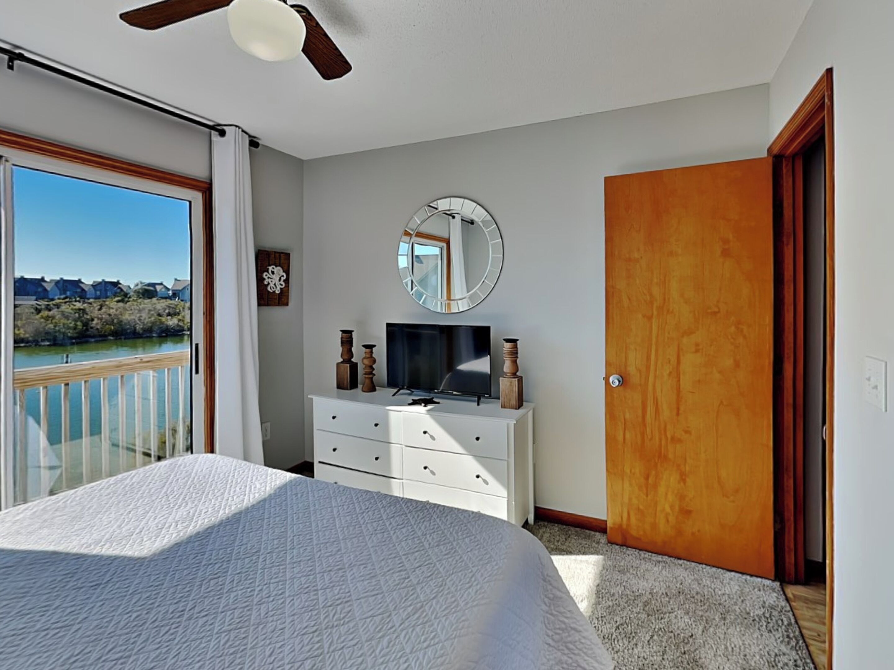 Un dormitorio con cama, cómoda, televisor, espejo y puerta.