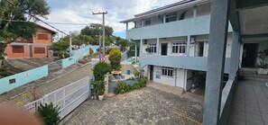 A residential building with a blue exterior, a gated entrance, and a small garden area with potted plants. - GH Ingleses (Florianopolis)