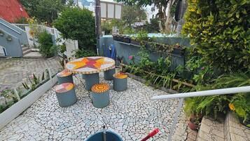 A courtyard with a mosaic-tiled floor, a star-patterned table, and grey cylindrical stools.