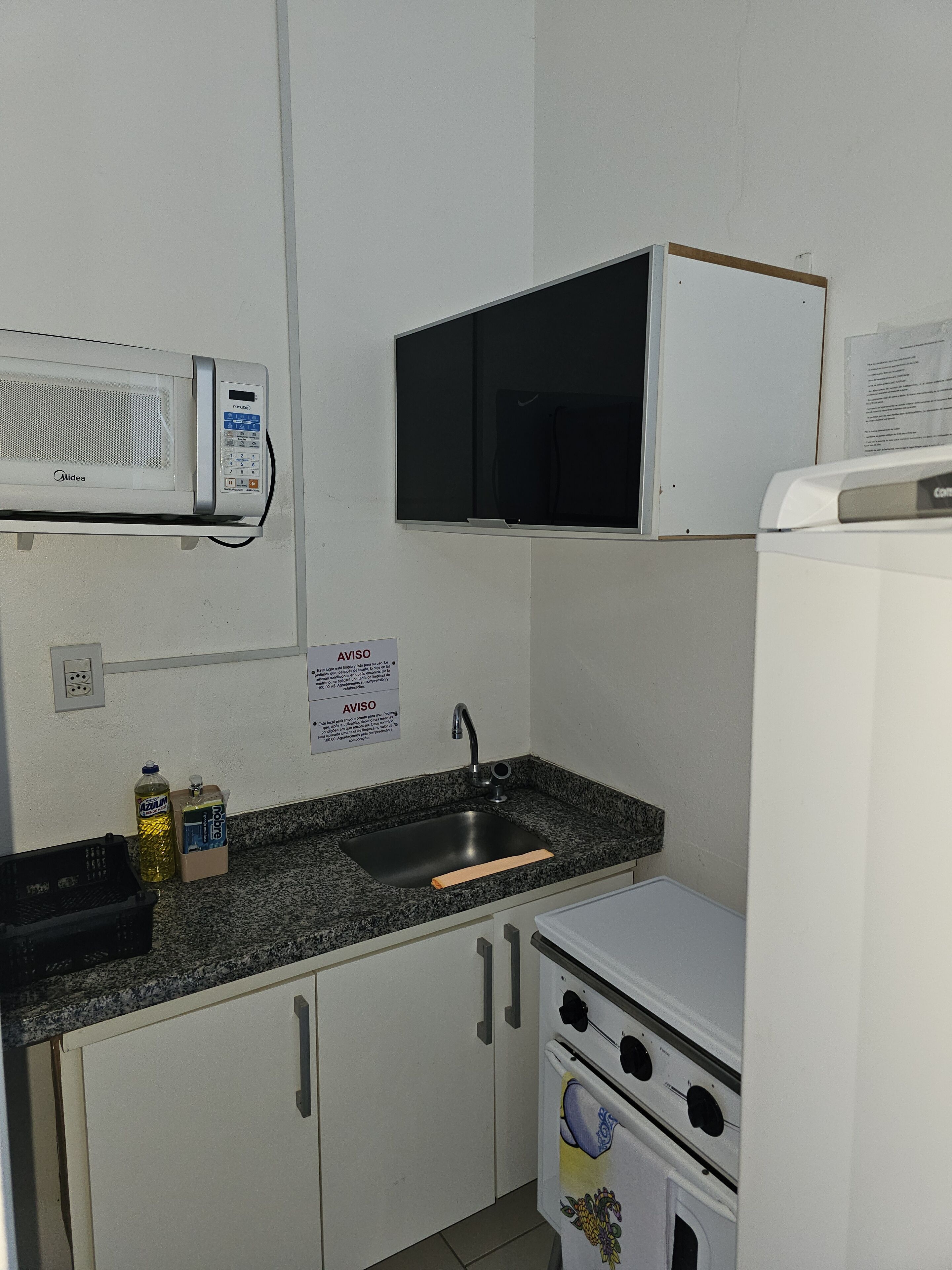A compact kitchen with a built-in microwave, a small sink, and a refrigerator.