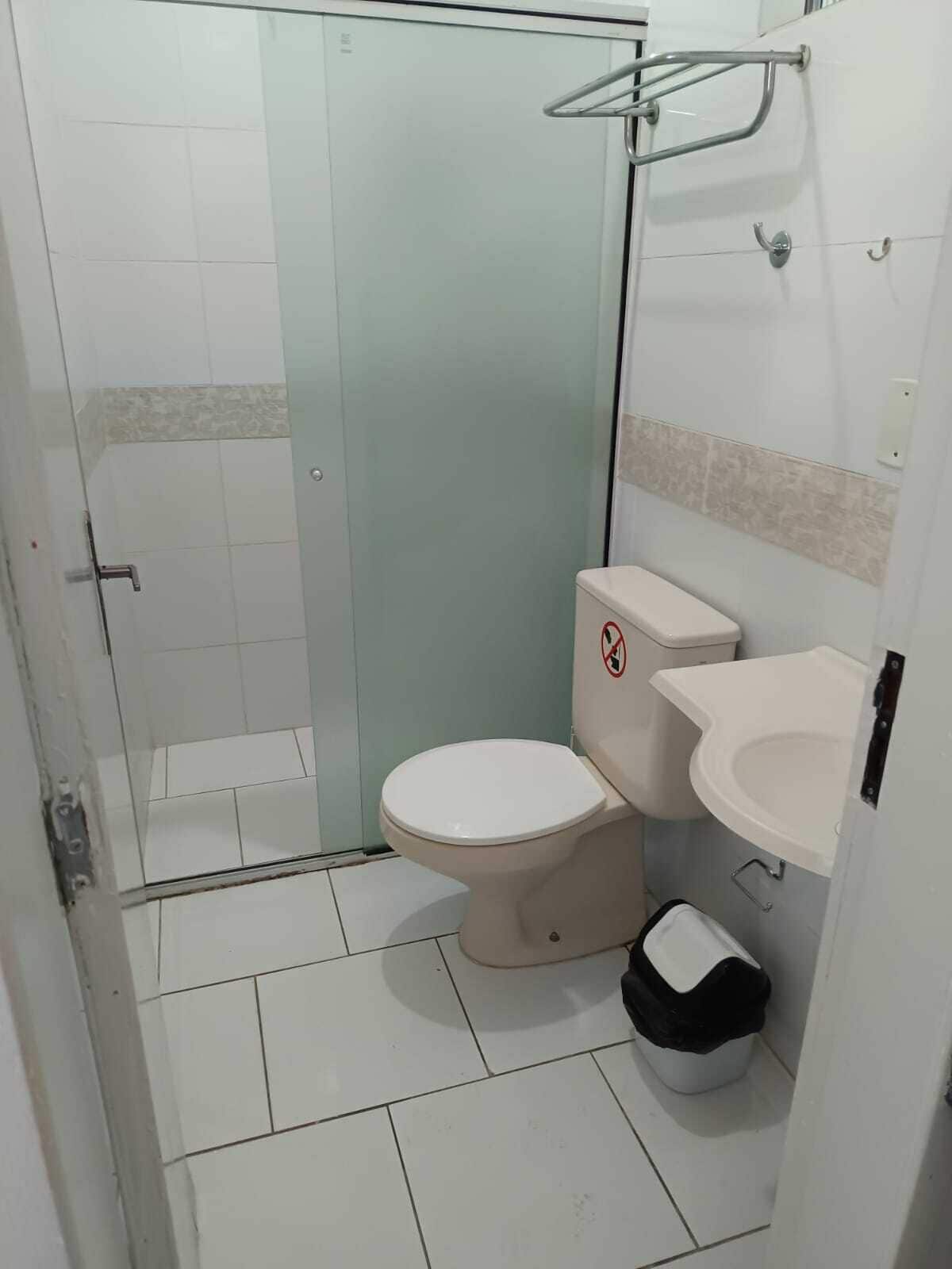 A small bathroom with a toilet, sink, and shower area.