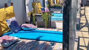 A covered outdoor seating area with a blue mat, cushions, and potted plants. - Cabane de Gardian unique in Petite Camargue Total disconnection unusual accommodation (Vestric et candiac)