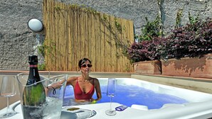 A woman in a red swimsuit sitting in a hot tub with a bottle of champagne and a glass. - Mira Suite (Vietri sul Mare)