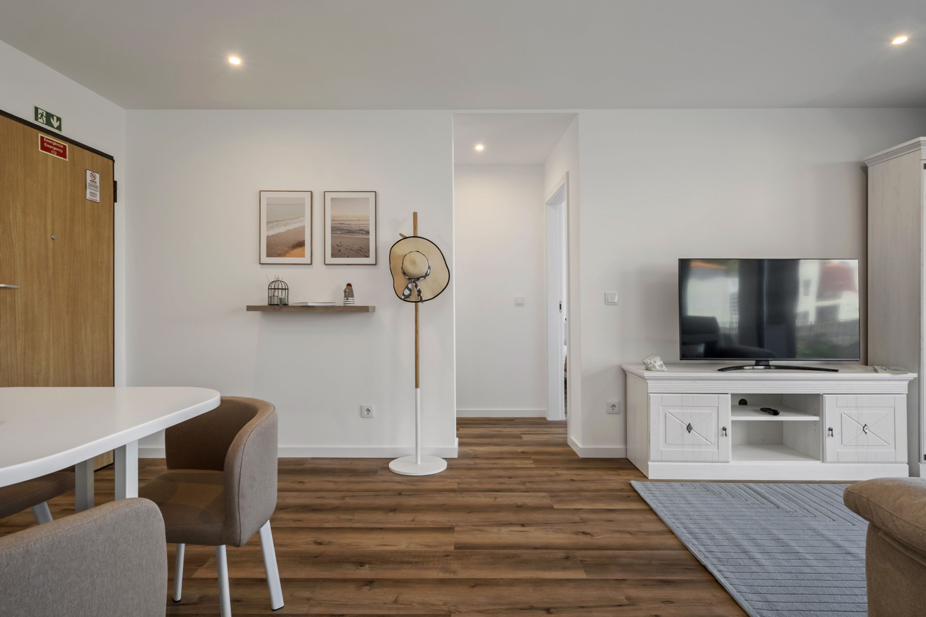 Un salon moderne avec un meuble TV blanc, une table à manger avec des chaises et un lampadaire.