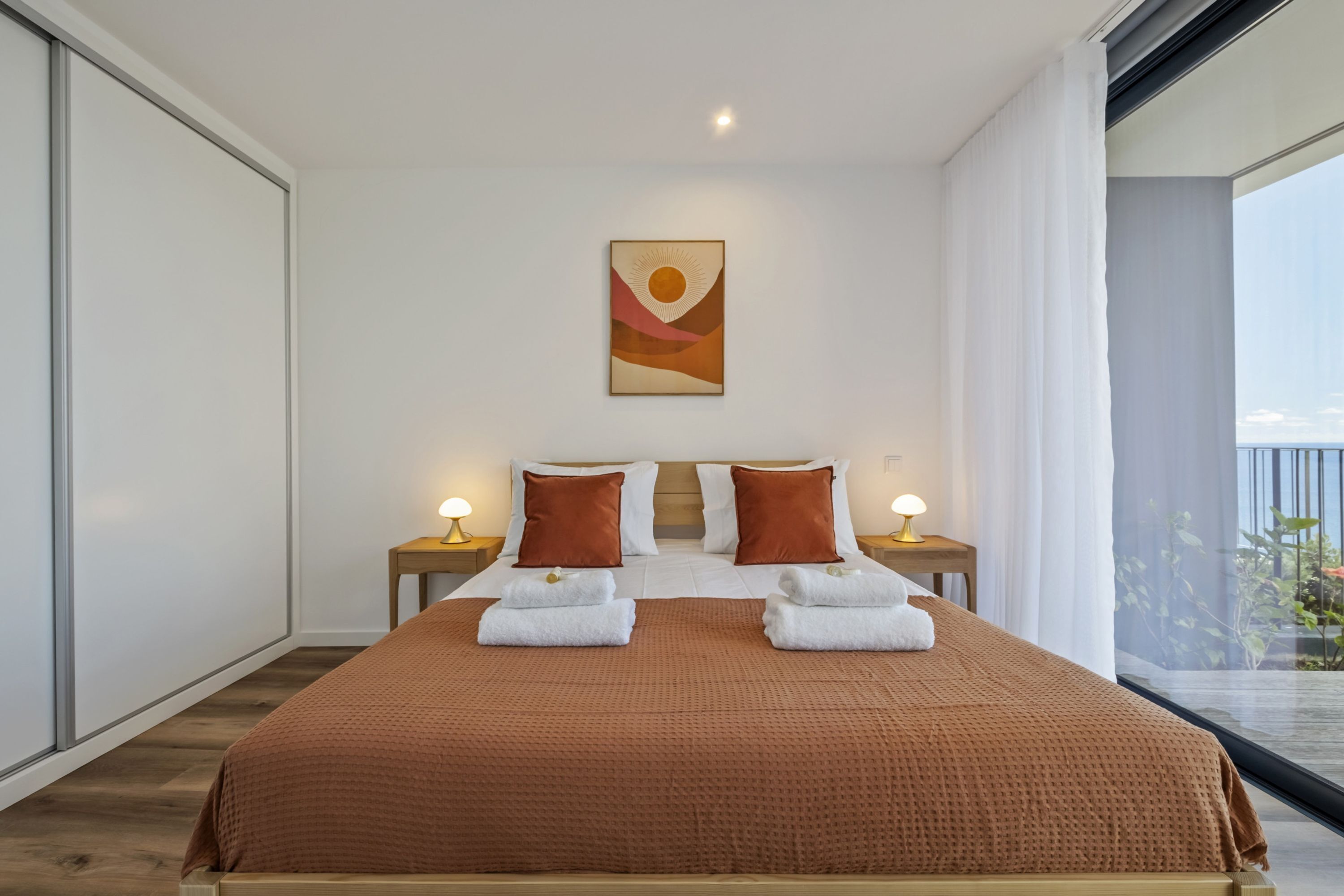 Habitación de hotel moderna con una cama grande, dos almohadas, una colcha marrón y un cuadro en la pared.