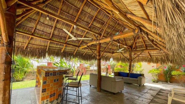 Un espace extérieur abrité, doté d’un toit de chaume, de sièges et d’un bar carrelé.