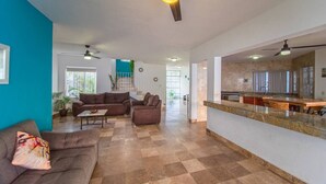 Un amplio salón con sofá, mesa de centro y una zona de cocina con encimera y electrodomésticos.