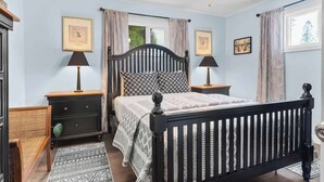 A bedroom with a bed, two bedside tables, a nightstand, a ceiling fan, and two framed pictures on the wall. - Family retreat walk to lake with bikes and games (Coeur d'Alene)