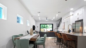 A modern kitchen with a central island, bar stools, and a dining area with chairs. - Modern 3BD/2.5 B in The heart Houston minutes from Downtown /Heights (Houston)