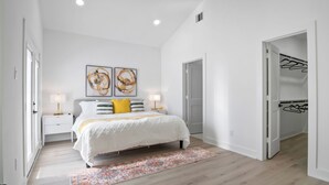 A bedroom with a bed, two bedside tables with lamps, a rug, and a closet with hanging clothes. - Modern 3BD/2.5 B in The heart Houston minutes from Downtown /Heights (Houston)