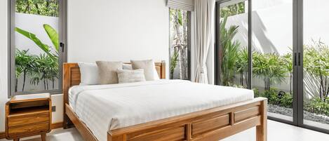 Quarto moderno com cama de madeira, mesa de cabeceira e amplas janelas com vista para o verde.