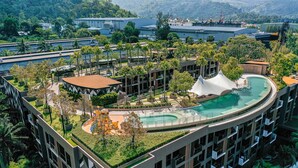 Un resort con piscina en la azotea, exuberante vegetación y arquitectura moderna.