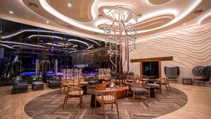 Un área de estar moderna con un diseño de asientos circulares, un elemento decorativo de iluminación central y vistas a una piscina al aire libre.