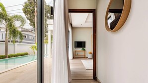 Un interior moderno con suelo de madera, un televisor sobre un mueble y vista a una piscina exterior.