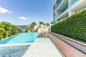 Une piscine avec une terrasse en bois et vue sur un immeuble doté de balcons.