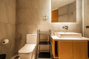 Un baño moderno con inodoro, lavamanos y espejo.