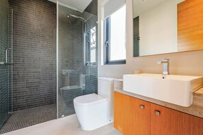 A modern bathroom with a glass-enclosed shower, a white toilet, and a wooden vanity with a sink. - Botanica Modern By Villacarte 159/38 (Si Sunthon)