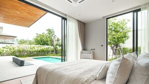 Un dormitorio moderno con una cama grande, vista a una piscina y un ventanal corredero que da a un espacio exterior.
