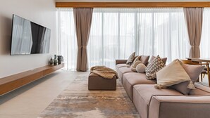 Una sala de estar moderna con un sofá, un reposapiés y un televisor de pantalla plana montado en la pared.