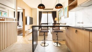 Une cuisine moderne dotée d’un îlot central, de luminaires suspendus et offrant une vue sur l’extérieur.