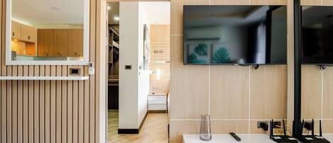 A modern living room with a wooden panel wall, a mounted TV, a clock, and a minimalist console table.