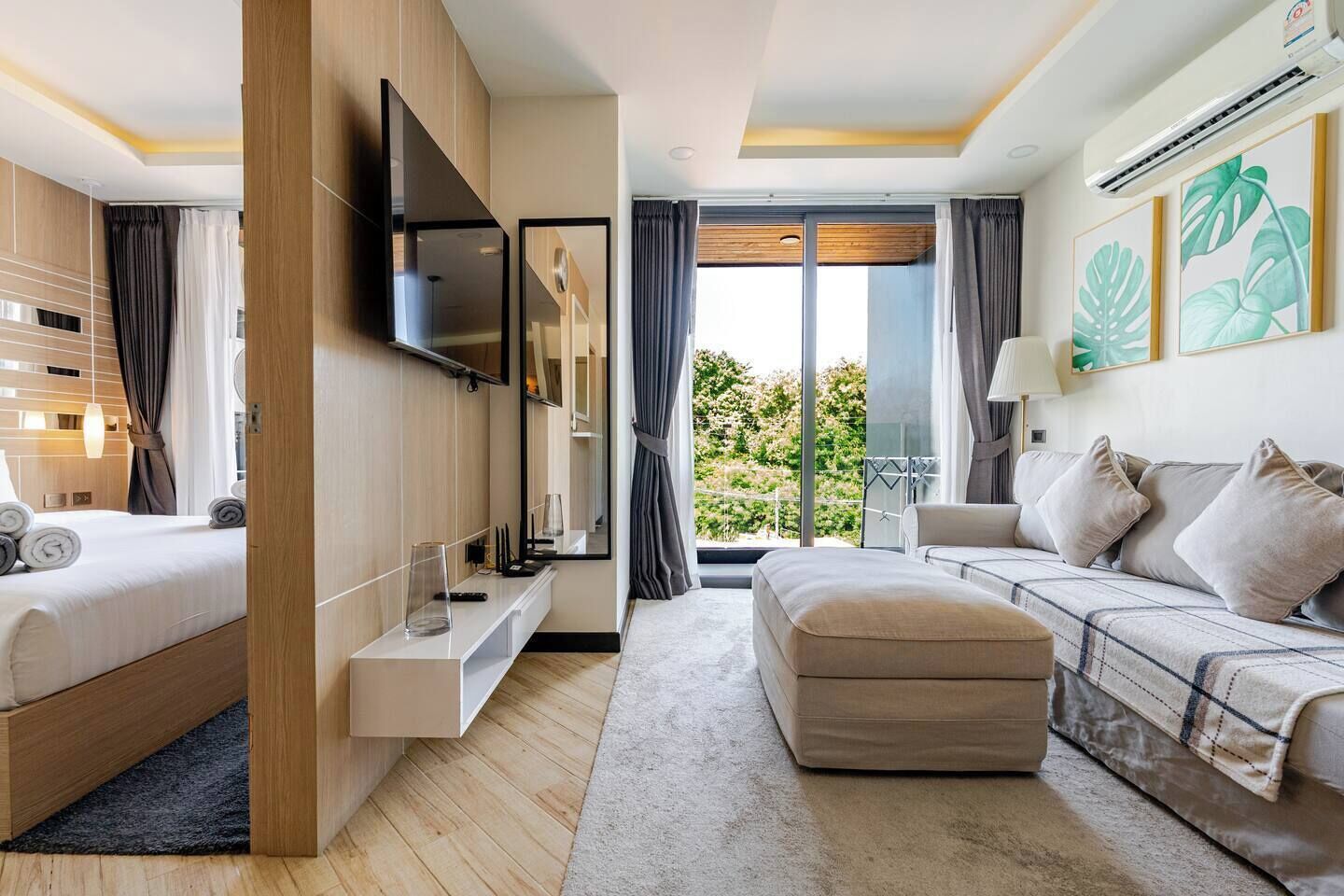 Une chambre d’hôtel moderne équipée d’un lit, d’un canapé, d’une télévision et d’un balcon avec vue.