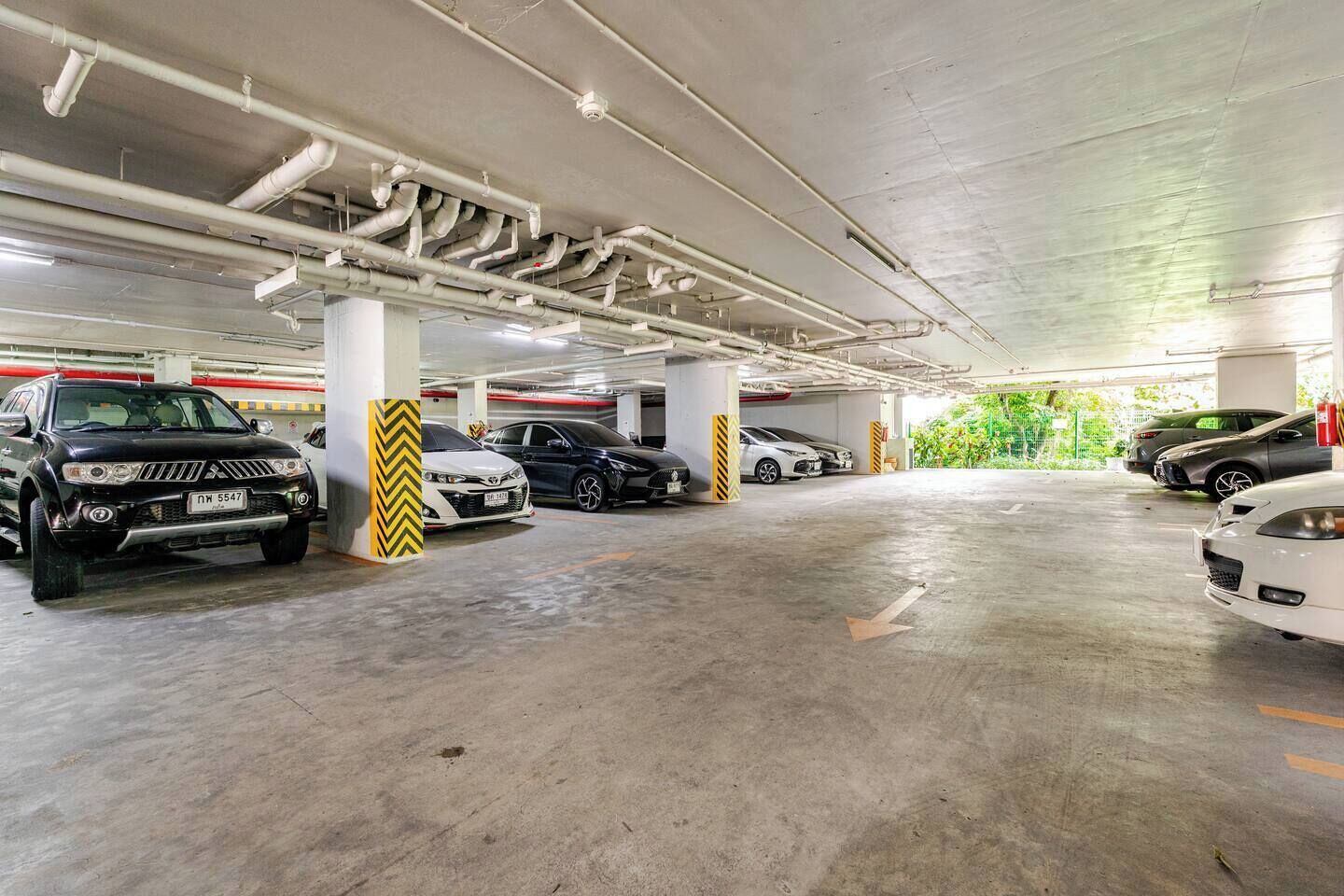 Eine mehrgeschossige Tiefgarage mit Betonböden und -säulen, in der sich mehrere Autos befinden.