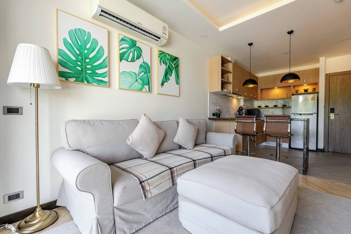 Ein modernes Wohnzimmer mit einer Couch, einem Couchtisch, einer Lampe und einer Küche im Hintergrund.