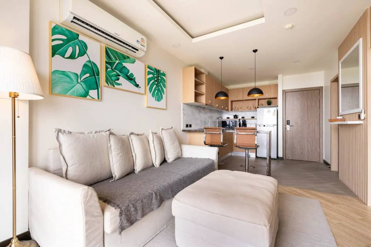 A modern living room with a sofa, a coffee table, and a kitchen in the background.