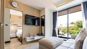 Une chambre d’hôtel moderne équipée d’un lit, d’une télévision, d’un canapé et d’un balcon avec vue.