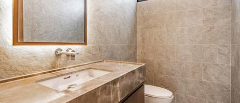 A bathroom with a marble sink, a toilet, and a large mirror.