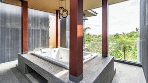 Un baño moderno con una bañera independiente, vigas de madera y vista a zonas verdes.