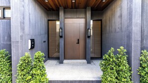 Una entrada de edificio moderna con techo de madera, una puerta central y dos puertas laterales.