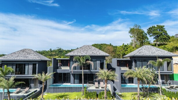 Un moderno resort con tres edificios conectados, cada uno con piscina y sillones de descanso.