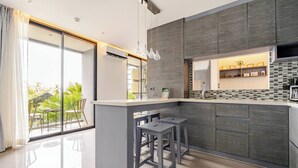 Una cocina moderna con una isla central, taburetes de bar y vistas al exterior.