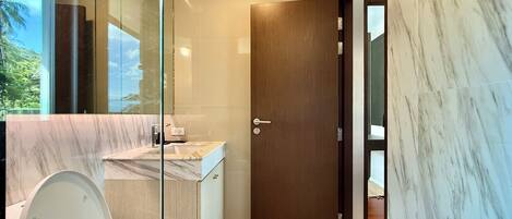 Un baño moderno con inodoro, lavabo y zona de ducha.